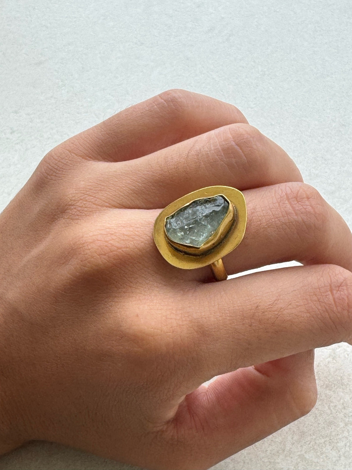 Anillo Tetis dorado con aguamarina puesto en la mano