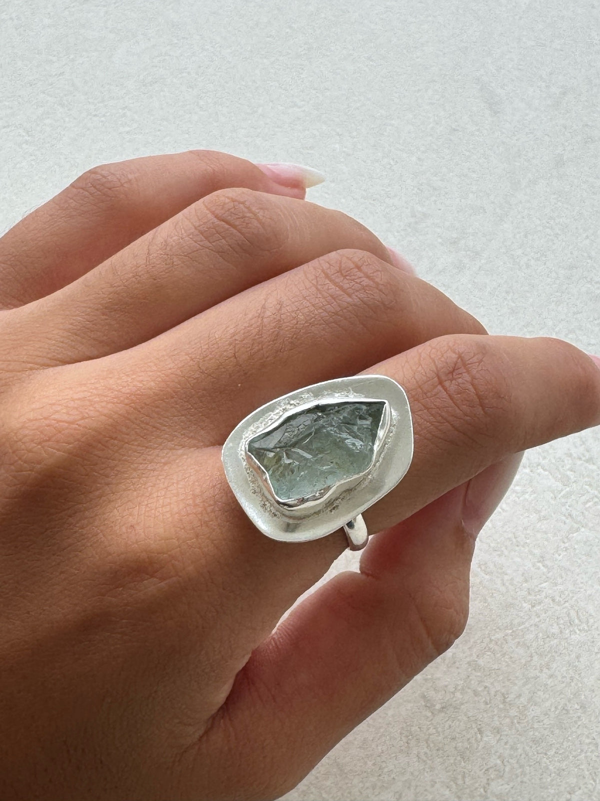 Anillo Tetis plateado con aguamarina puesto en la mano